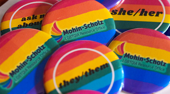 buttons with the Mohin-Schulz LGBTQIA Resource Office logo and she/her, they/them