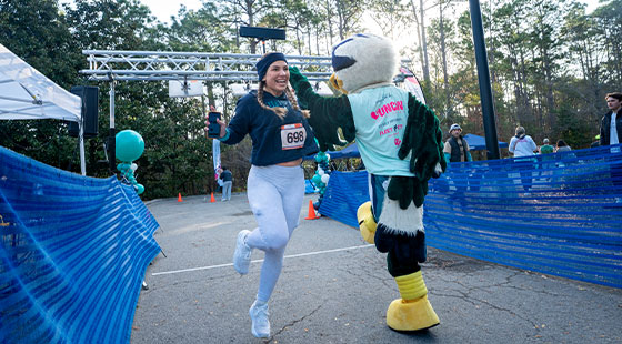 Runner finishing and getting high five from Sammy C. Hawk
