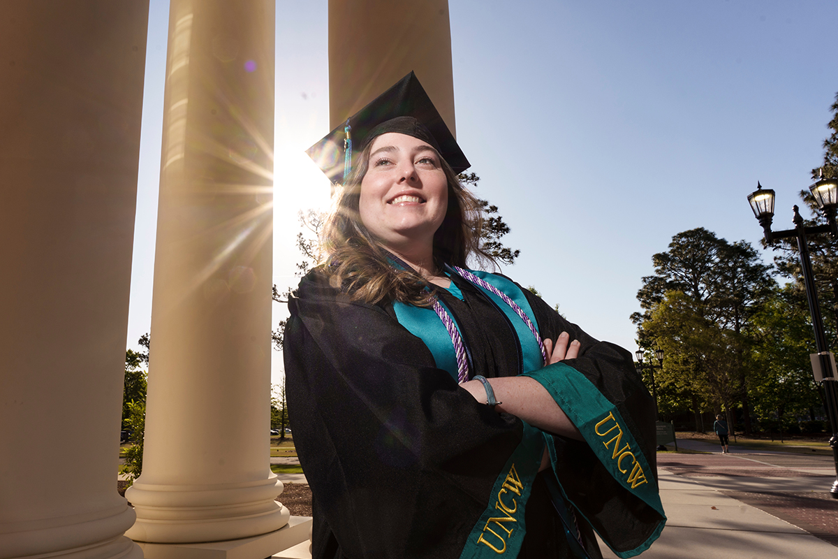 UNCW graduate in front of columns on campus