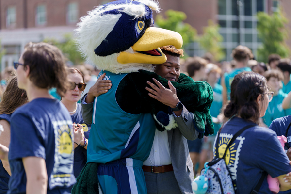Sammy hugging student in a crowd of Seahawks