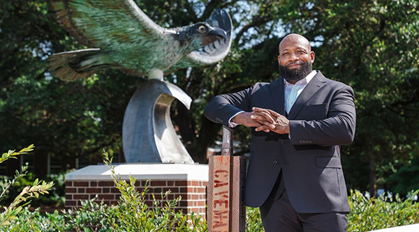 Justin Hickman standing infront of the Seahawk Statue