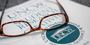 Reading glasses resting on a student research book