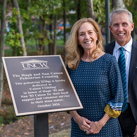 Hugh and Nan Caison pose for a photo next to a plaque.